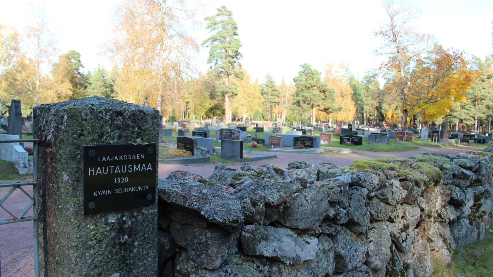 Kivimuurin takana hautakiviä.