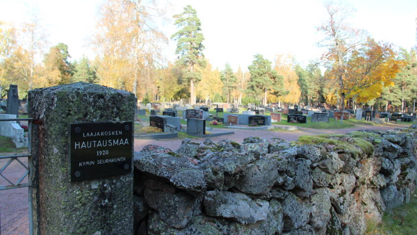 Kivimuurin takana hautakiviä.
