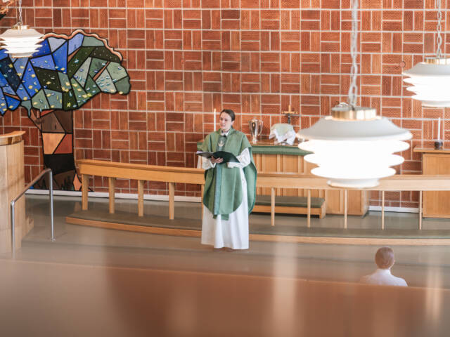 Alttarilla pappi pukeutuneena liturgisiin vaatteisiin.