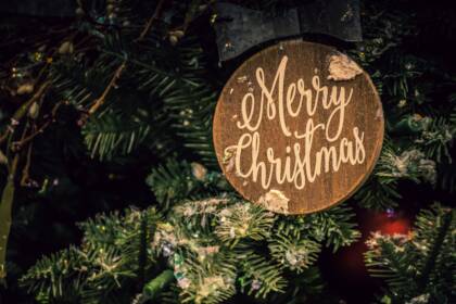 Kuusenoksia ja kyltti, jossa teksti "merry christmas".
